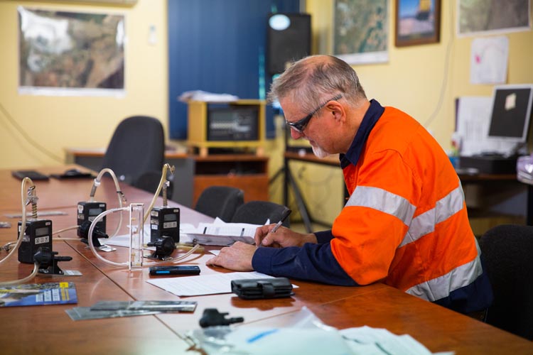 Worker recording results from dust monitoring